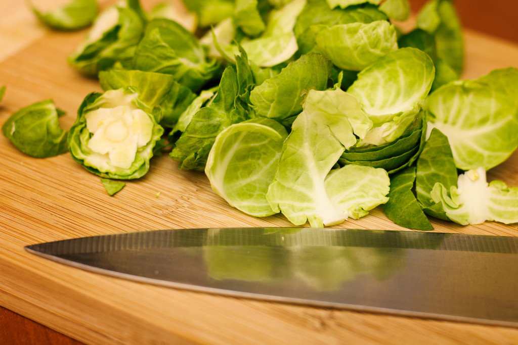 Raw Brussels sprouts on a cutting board with a knife