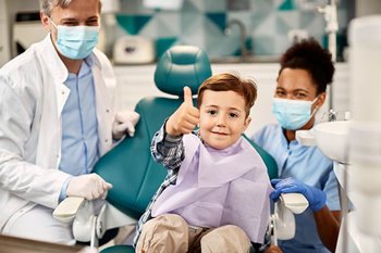 Child at dentist giving thumbs up